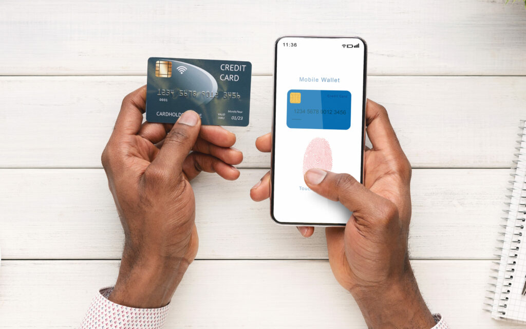 Uma pessoa segurando um cartão de crédito e um smartphone com uma carteira digital na tela