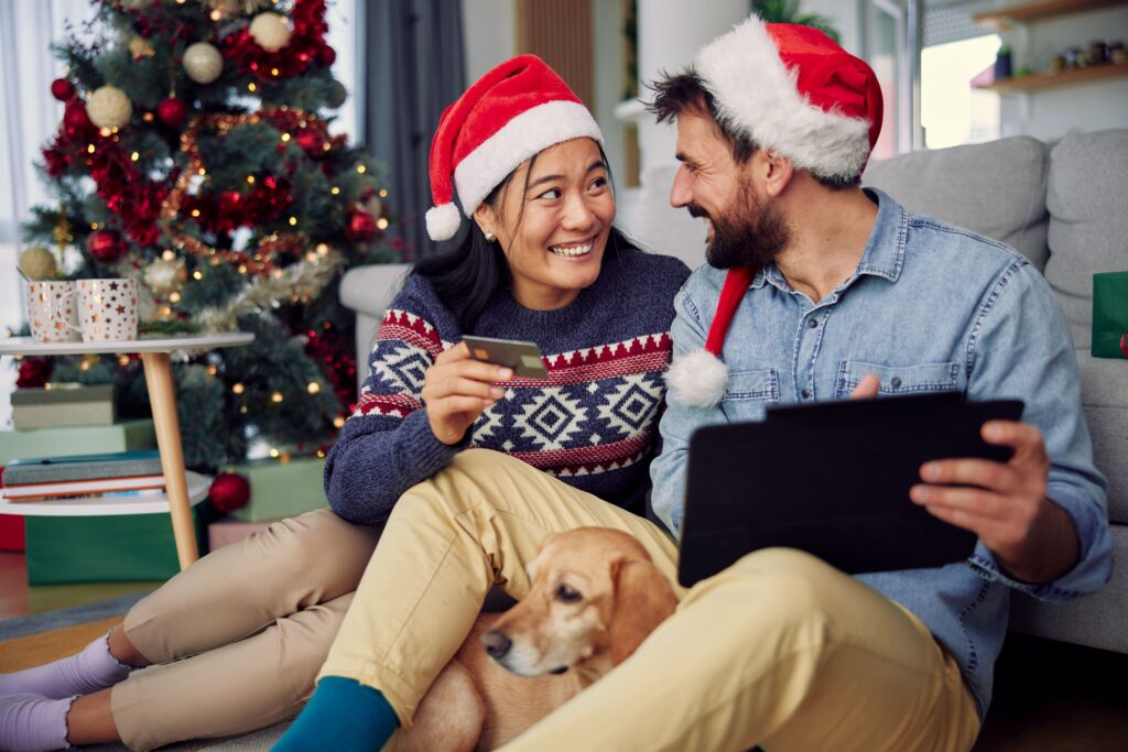Homem e mulher comemorando natal acompanhados de um cão