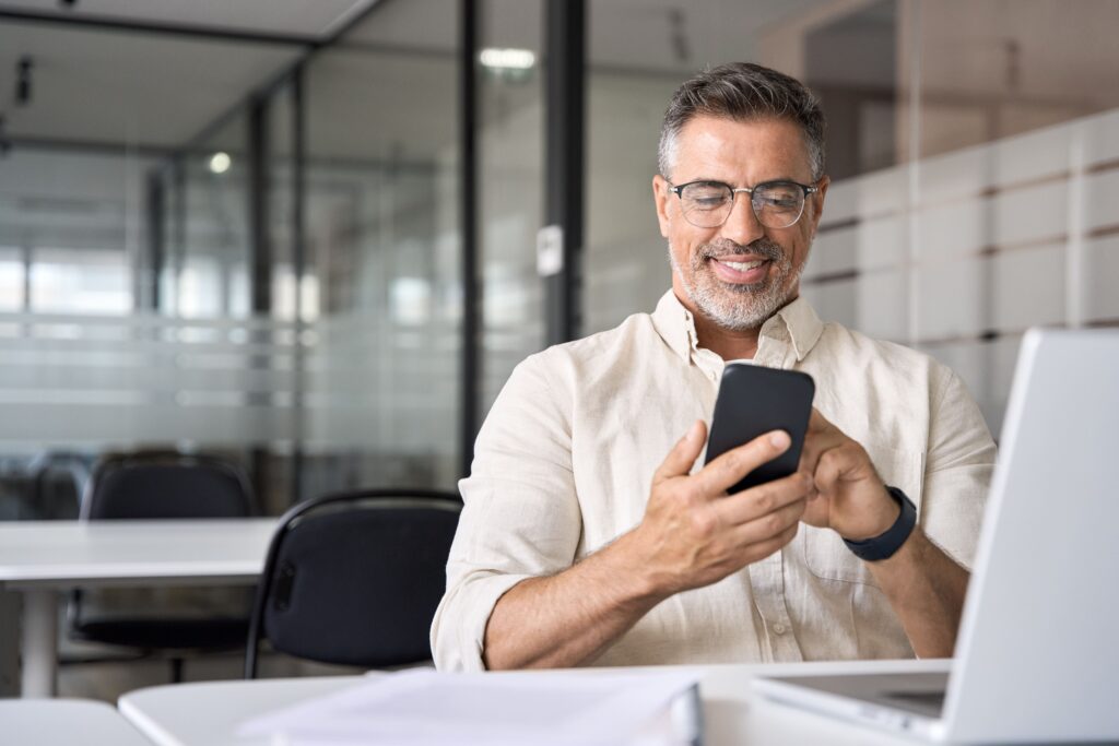 Homem sorrindo enquanto mexe no celular