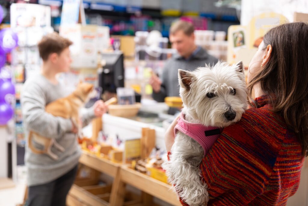 Mulher segurando cão no pet shop enquanto um homem faz o pagamento no balcão