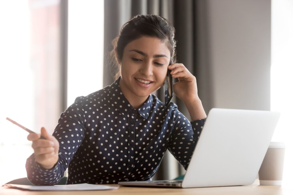 Mulher falando no telefone enquanto segura um lápis para fazer anotações