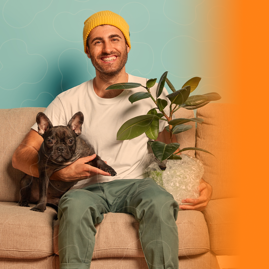 homem sentado no sofá com seu cão e segurando um vaso de planta