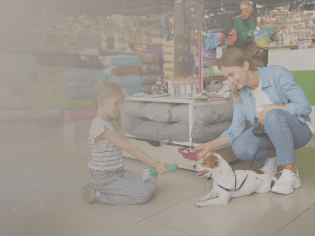 Mulher e menina oferecendo itens do pet shop ao cão