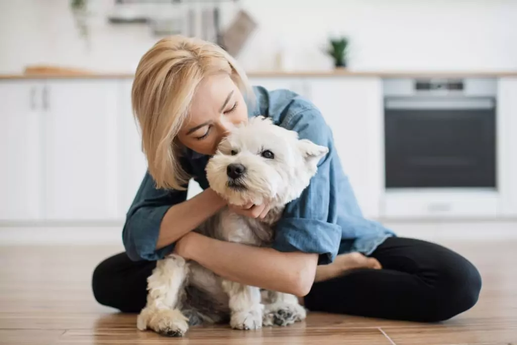 Tutora abraçando e beijando seu cão