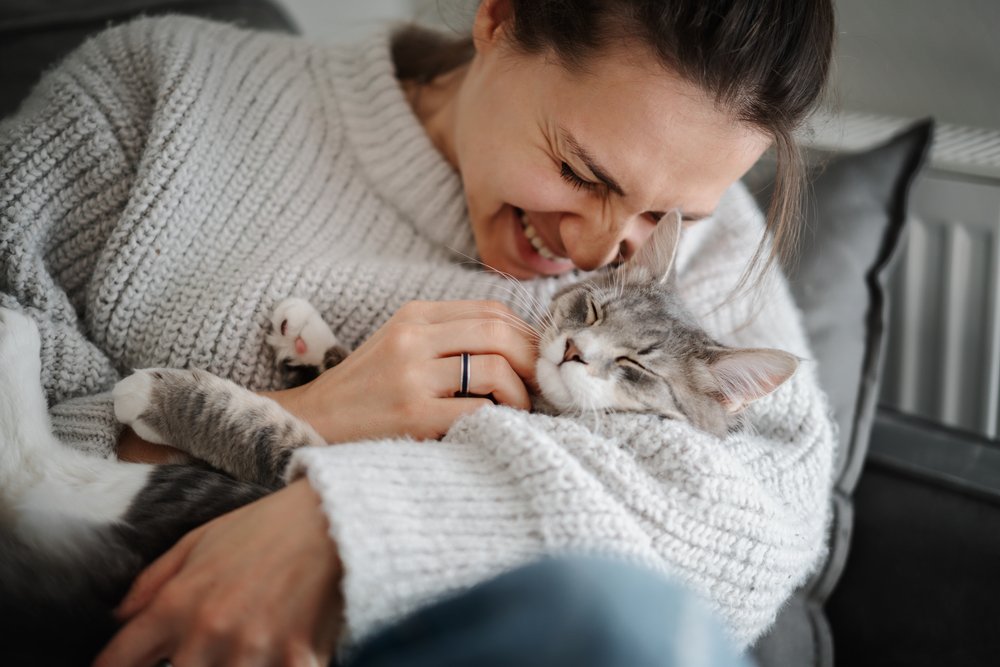 Tutora sorrindo e fazendo carinho em seu gato