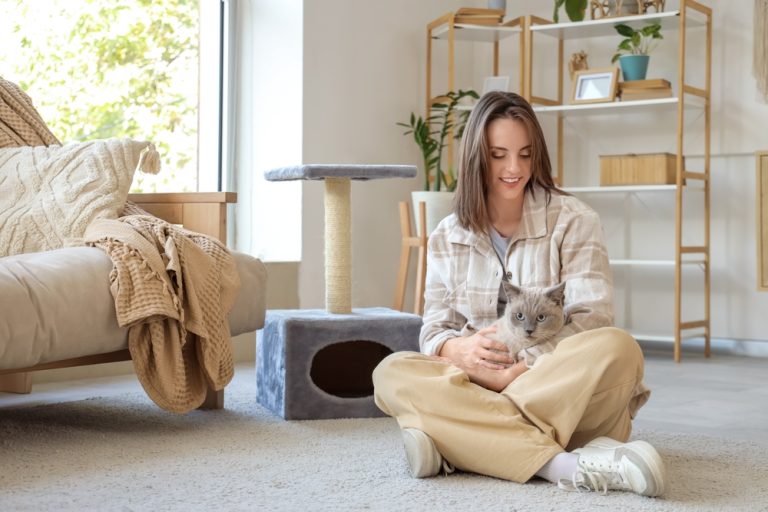 Mulher com gato no colo dentro de casa